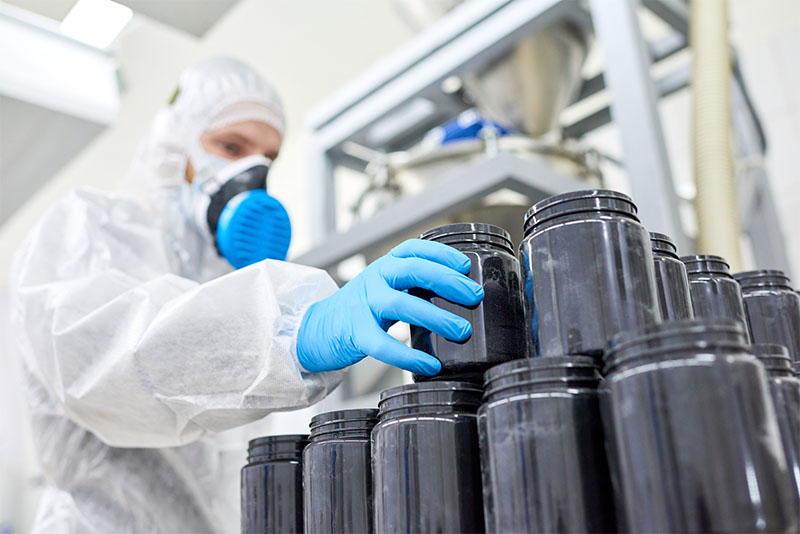 Factory employee inspecting plastic jar from manufacturing order of sports supplement, creatine, hmb, bcaa, amino acid or powdered vitamin. Sports nutrition production Factory employee inspecting plastic jar from manufacturing order of sports supplement, creatine, hmb, bcaa, amino acid or powdered vitamin. Sports nutrition production