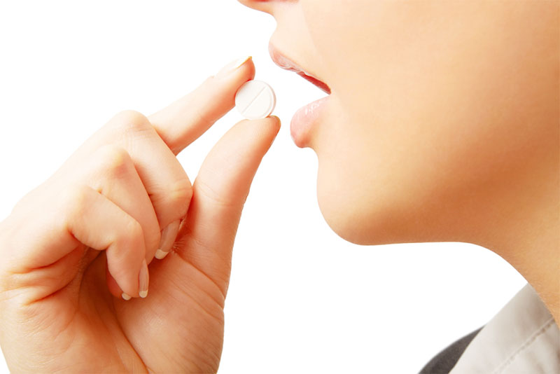 Close-up of a woman's hand holding a white dissolvable tablet near her mouth, ready to take a quick-melt tablet supplement. Close-up of a woman's hand holding a white dissolvable tablet near her mouth, ready to take a quick-melt tablet supplement.