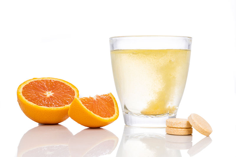 Series of orange flavored vitamin c effervescent tablet dropped and dissolve in glass of water on white background Series of orange flavored vitamin c effervescent tablet dropped and dissolve in glass of water on white background