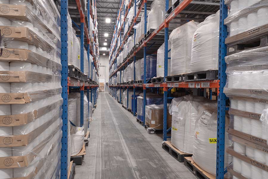 Vitaquest warehouse aisle with neatly stacked pallets of wrapped goods.