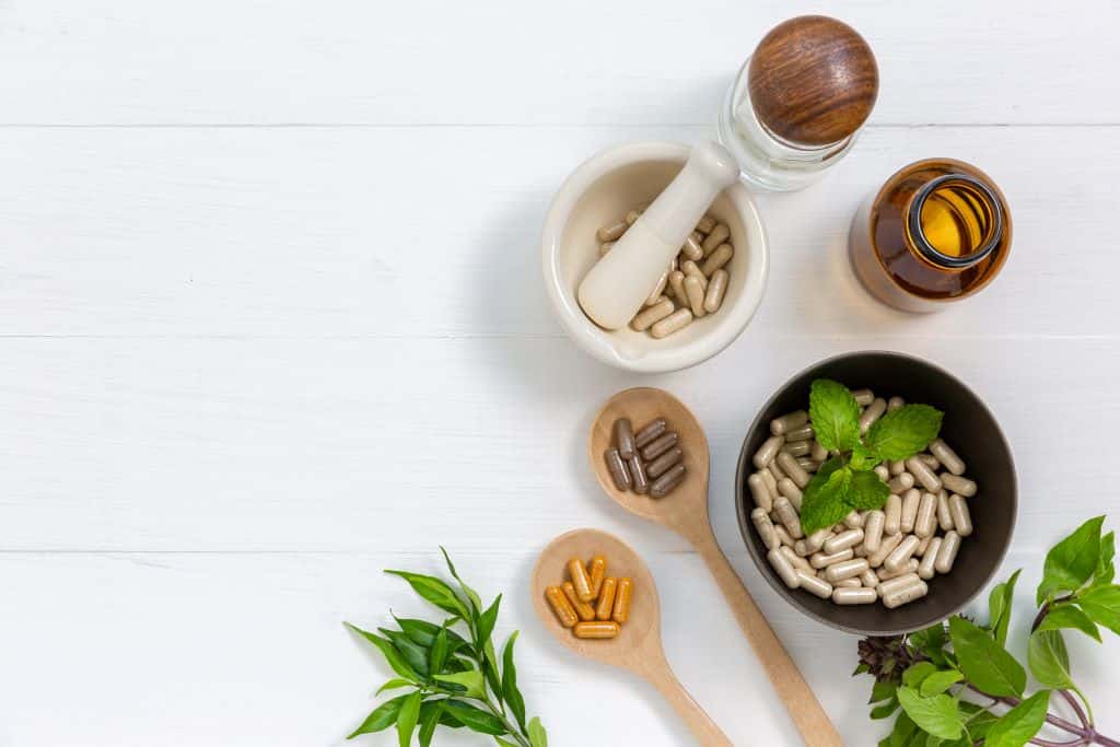 A collection of colored capsule supplements on wooden spoons and different size bowls.